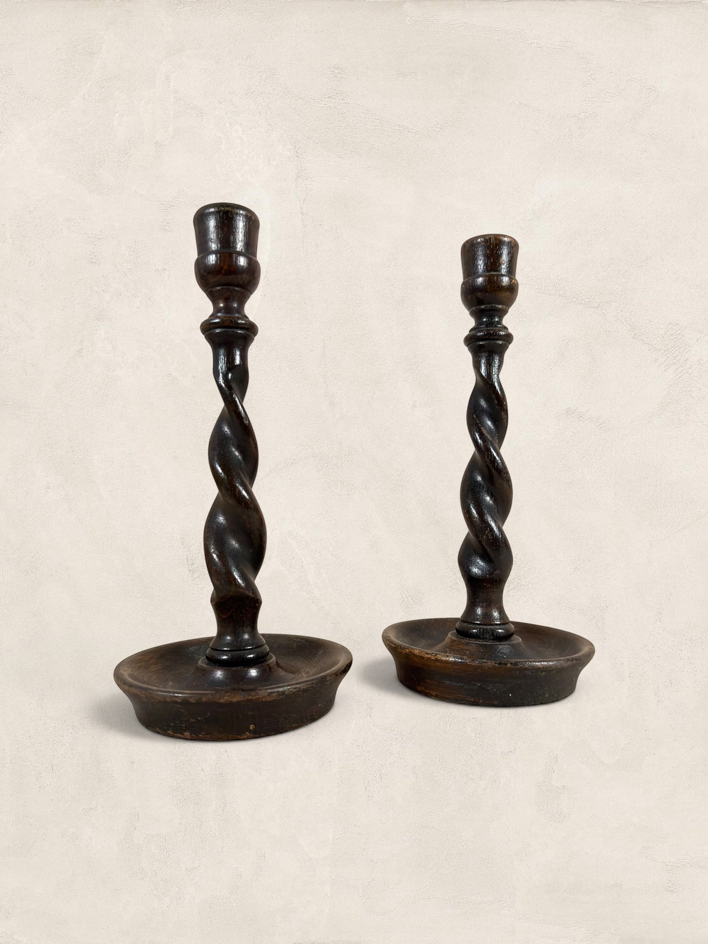 Stone and Relic antique dark oak barley twist candlestick holders, circa 1910. Pair of wooden candle holders with carved spiral stems and circular bases.