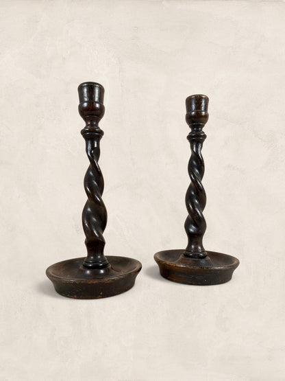 Stone and Relic antique dark oak barley twist candlestick holders, circa 1910. Pair of wooden candle holders with carved spiral stems and circular bases.