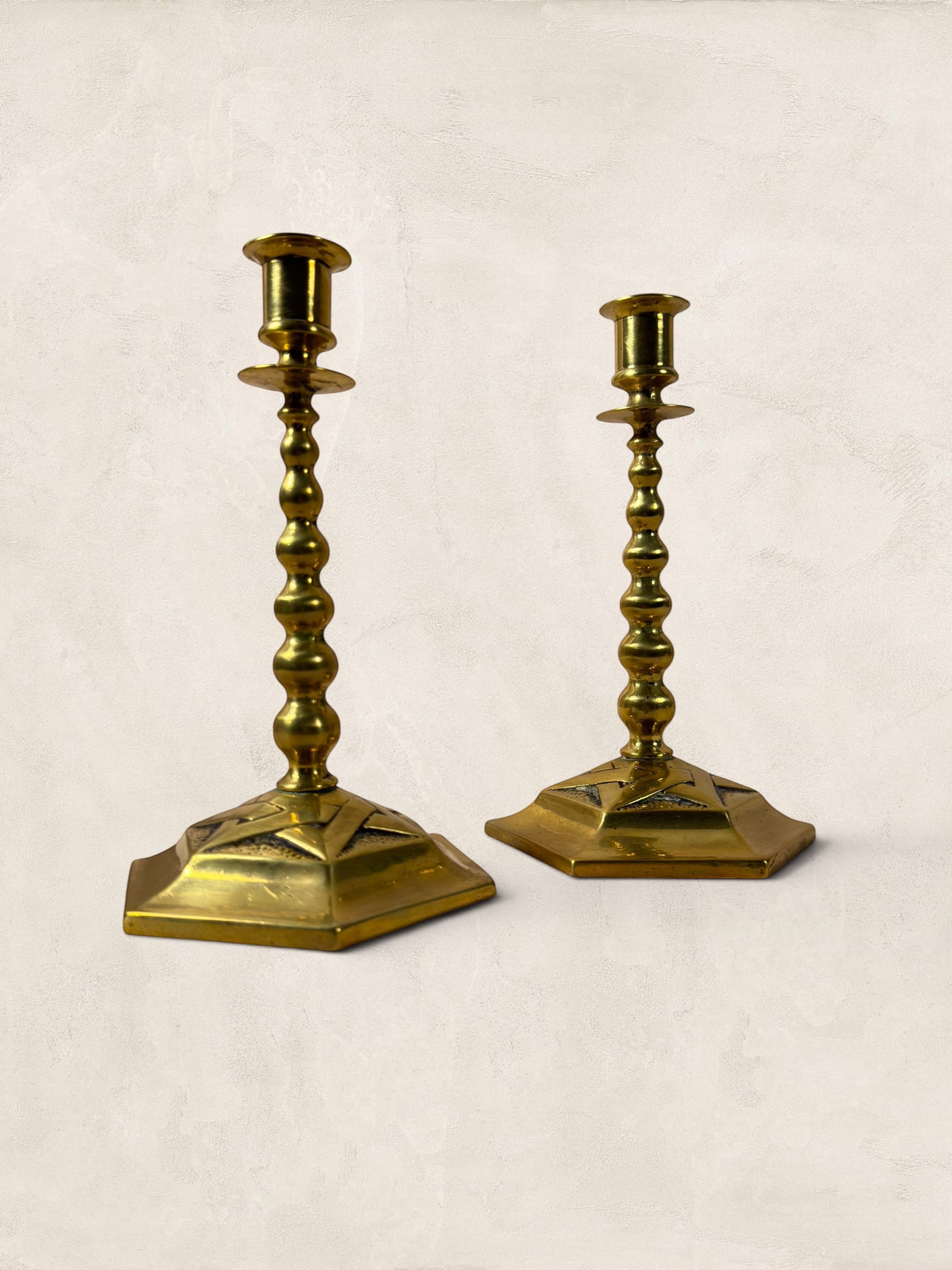 Stone and Relic pair of vintage brass hexagonal base candlesticks with aged patina and decorative stem.
